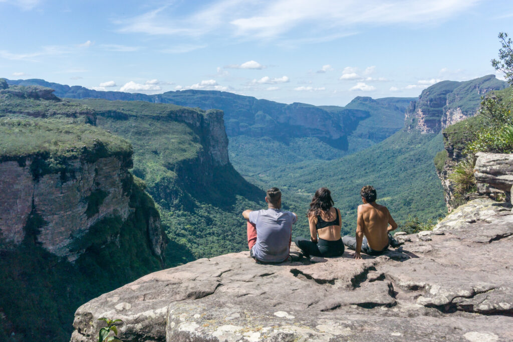 Three people standing on a plateau looking into the distance across a dramatic table mountain landscape