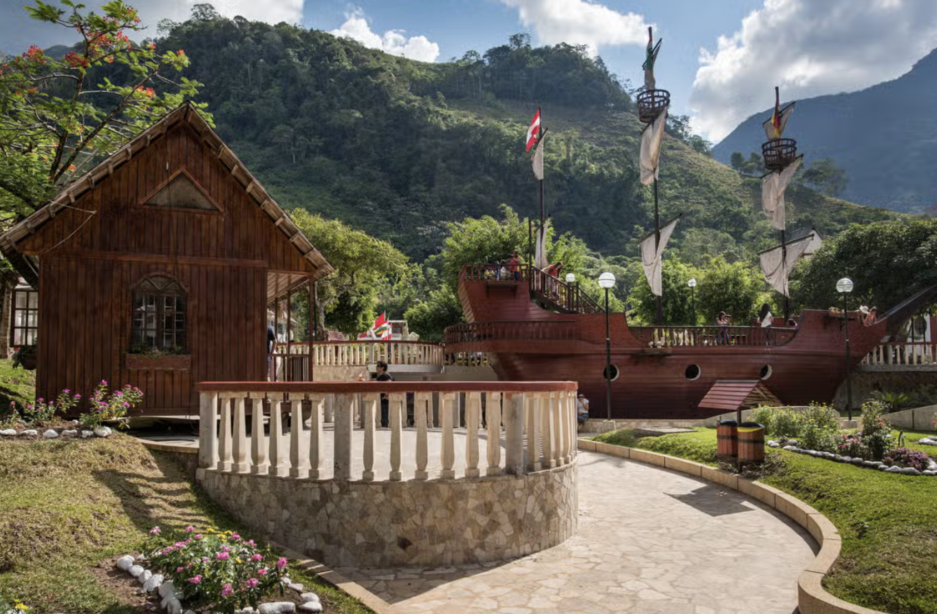 Alpine-style wooden houses in the Peruvian village of Pozuzo, surrounded by green mountains; an Austrian flag is flying in front of one of the buildings.
